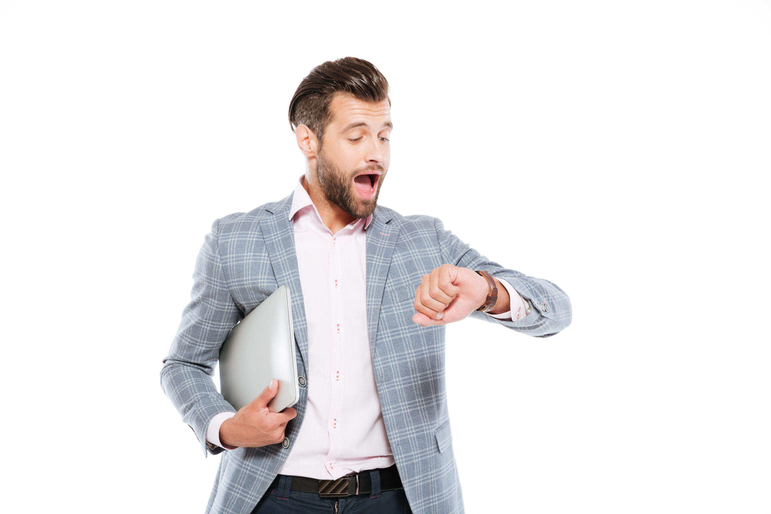 Image of screaming young man standing isolated over white background and holding laptop computer. Looking at watch.